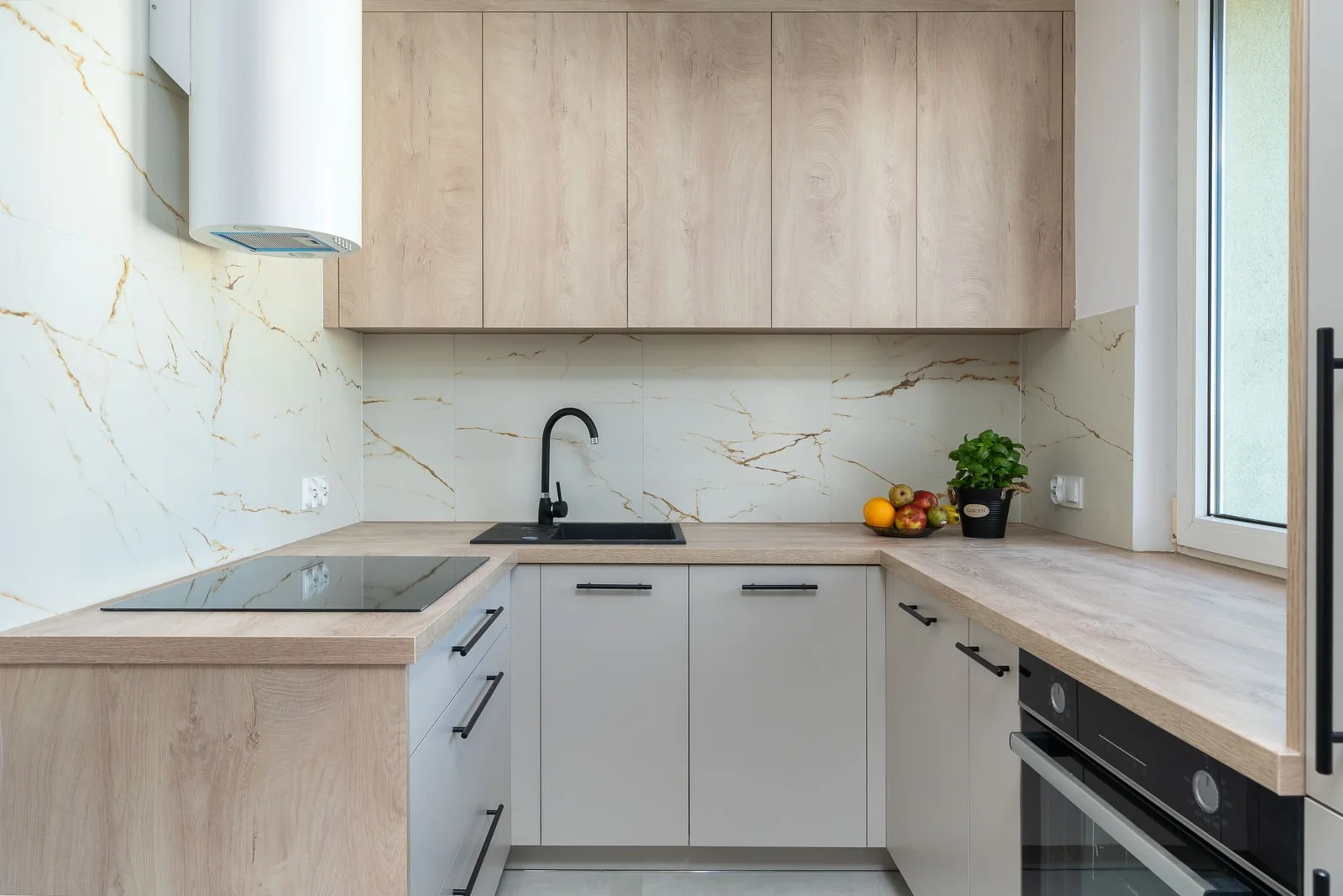 Lichte keuken met houten fronten, marmeren spatwand en zwarte kraan
